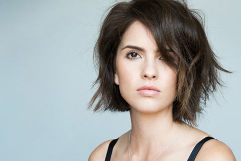 Shelley Hennig in a black dress poses a picture.